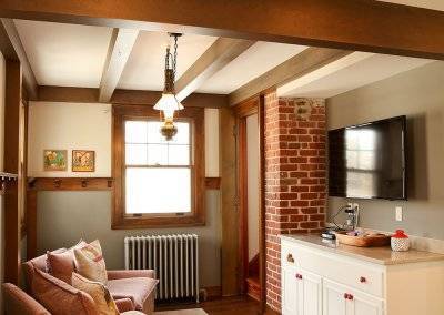A newly renovated space with wooden rafters, brick wall, and a TV.