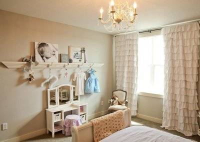 A bedroom with a large picture ledge and small princess vanity.