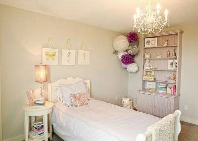 A child's bedroom with a twin bed and white decorations.