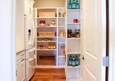 A large room with open shelving for groceries and a refrigerator.