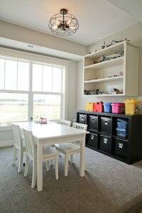 A white table with open shelving and cubby spaces behind it along the wall.