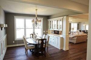 A dining room and living area are separated by built-in white cabinetry.