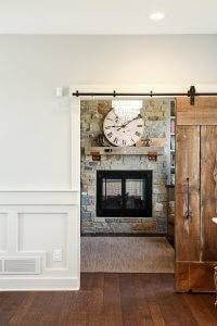An entryway through a sliding barn door where you can see a fireplace in the next room.