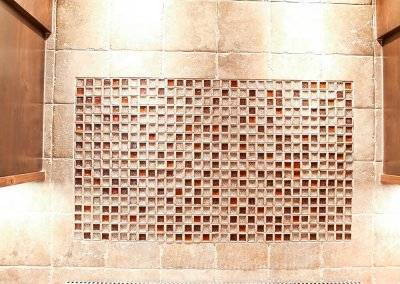 A tile backsplash behind and above a stovetop with amber colored accent tiles.