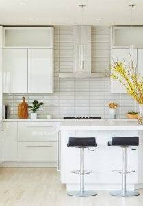 A remodeled kitchen with white cabinets, countertops, and backsplash.