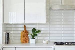a corner of a kitchen with white countertops. Recipe books, a cutting board, and a plant sit atop.