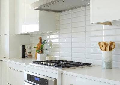 A white backsplash with stainless steel oven and range.