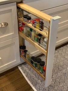 A built-in spice rack pulls out in a secret cabinet beneath a stovetop.