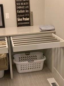 A bathroom countertop with drawers pulled out to reveal secret drying racks for hang-drying clothes.