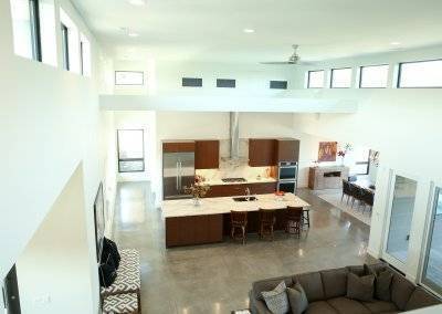 Loft view into modern kitchen and living space with loft windows and polished concrete floors.