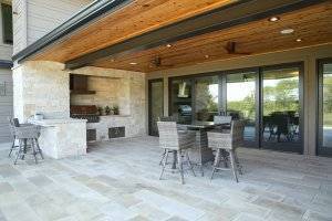 Outdoor kitchen and patio space with stone built ins, counter space and wood ceiling.