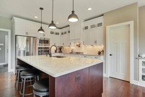 Kitchen featuring island with counter seating, pendant lighting, white cabinetry and pantry.