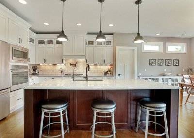Kitchen with white cabinetry and tile back splash, counter space seating and built in buffet/display.
