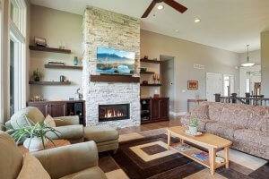 Great room featuring custom built in cabinetry, floating shelves, stone fireplace and hardwood flooring.