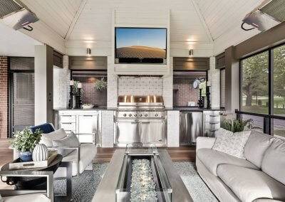 Outdoor kitchen with custom built ins, fire table, outdoor furniture and shiplap ceiling.
