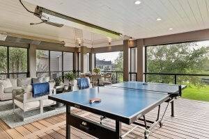 Ping Pong table on covered deck with drop down screens. Seating and dining area overlooking lawn.