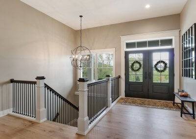 Front entry way with double doors and open stairway into the lower level.