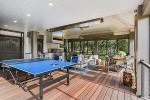 Outdoor kitchen with ping pong table, dining area and couches.