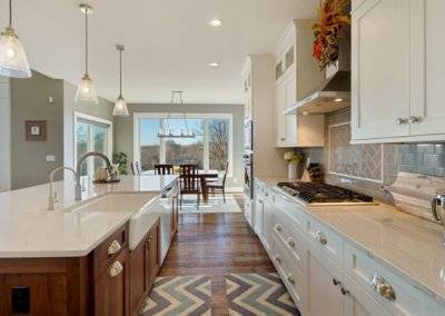 Two toned kitchen in gray and white, island with pendant lighting and farmhouse sink.
