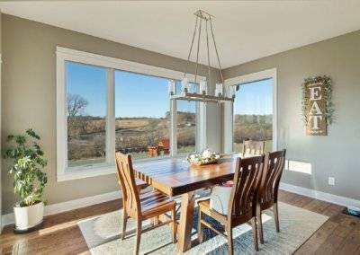 Dining space with table, rug and windows with country view.