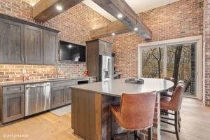 Wet bar with ceiling beams, brick accent walls, island and walkout.