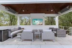 Outdoor tv area next to pool with heaters and seating.