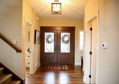 Entry with double doors, square light fixture, hardwood flooring.