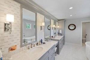Primary en suite with dual vanity, mirrors, tiled backsplash.
